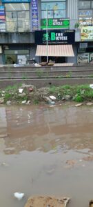 Children and parents struggle to cross the waterlogged Casa Greens 1 side service road, where rainwater mixed with foul-smelling STP discharge has turned the route into a hazardous stretch.